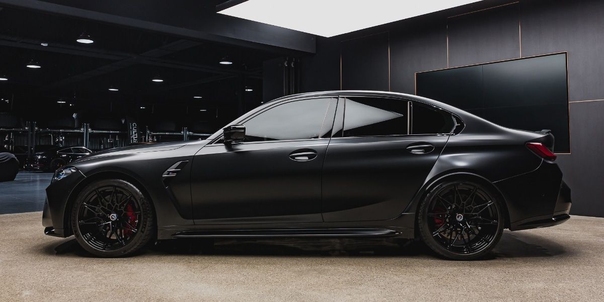 Sleek black luxury sedan parked inside a dimly lit showroom.